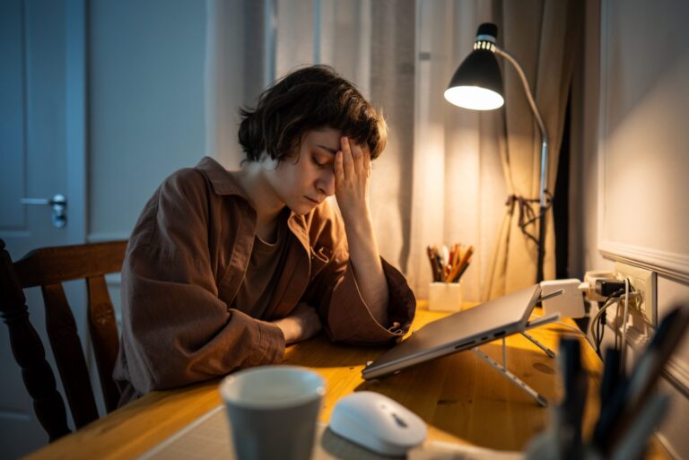 Tired woman resting her head after working late, a common sign of burnout
