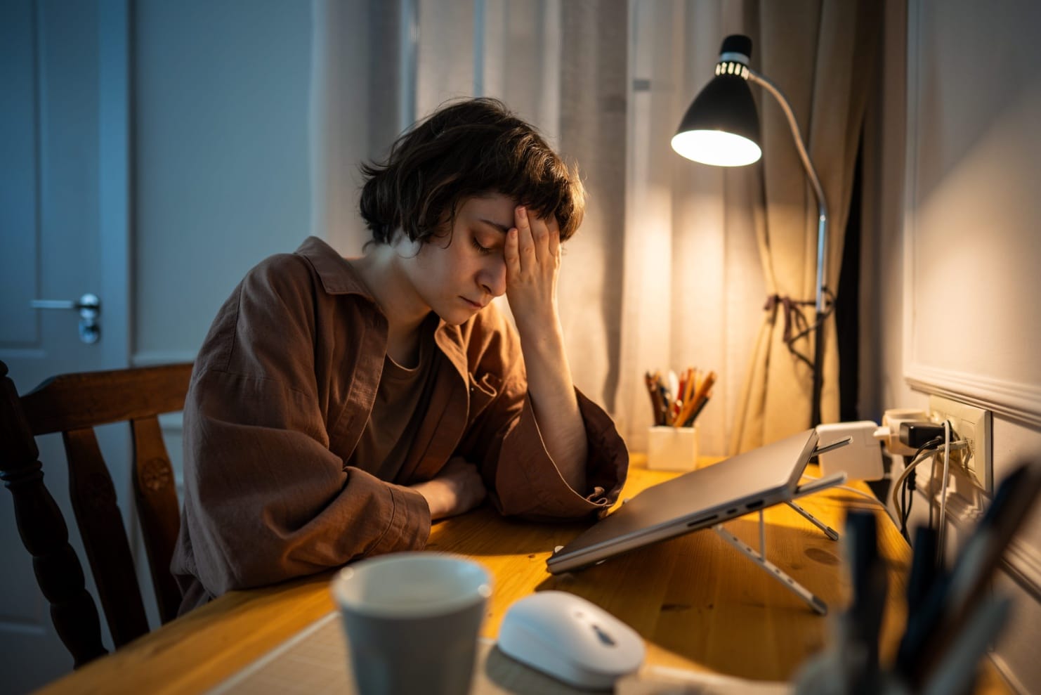 Tired woman resting her head after working late, a common sign of burnout
