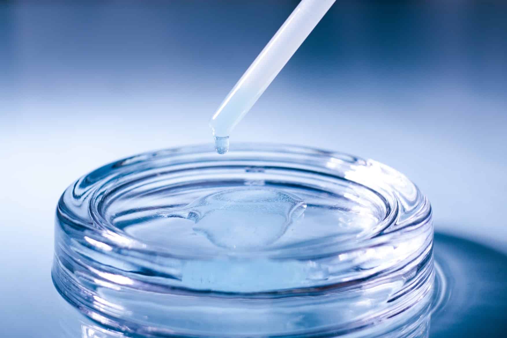 Close-up of GHK-Cu peptide serum being pipetted into a glass dish for skin treatment