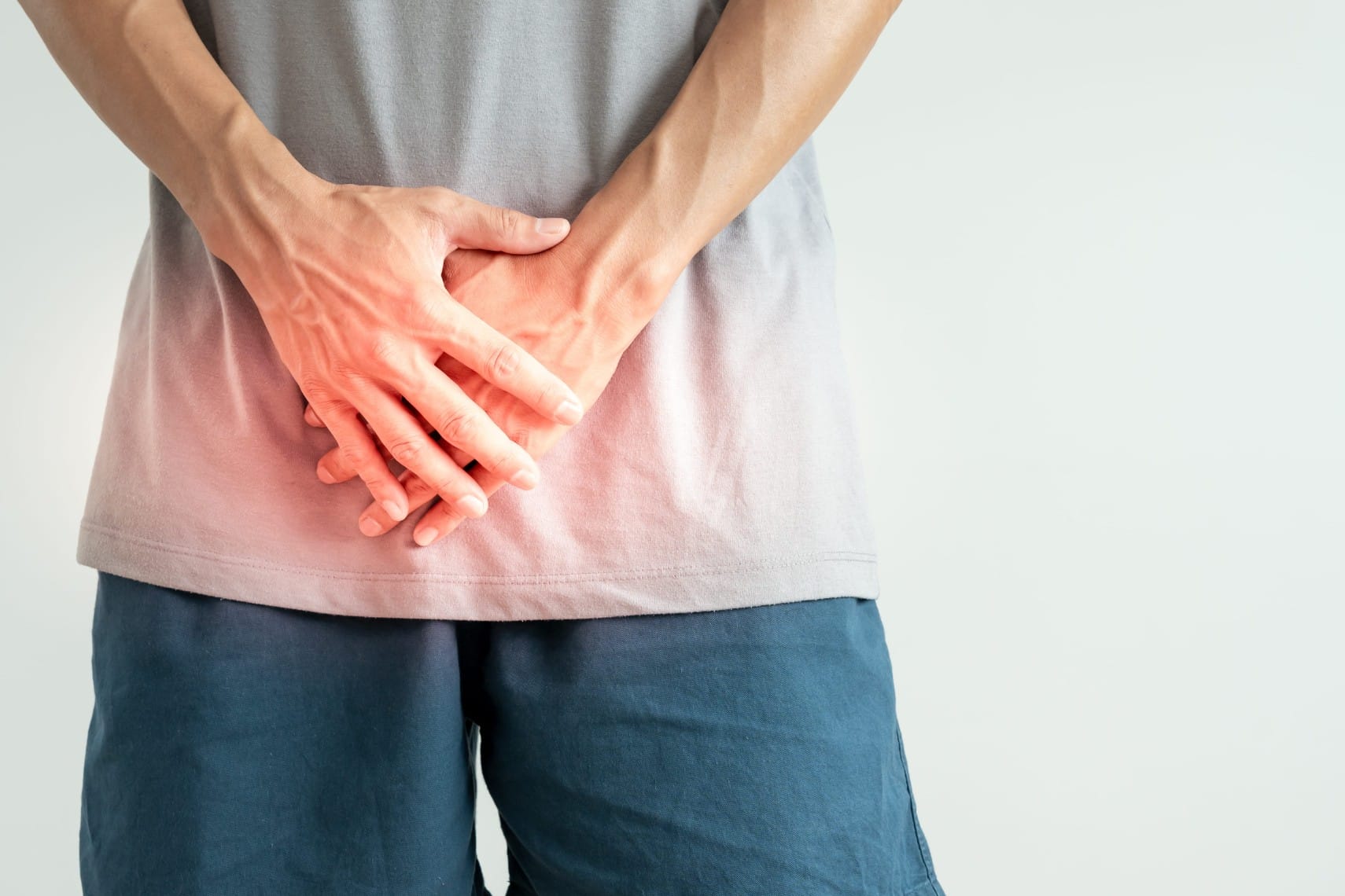 A man covers his groin with his hands. Painful urination is one symptom of gonorrhea in males.