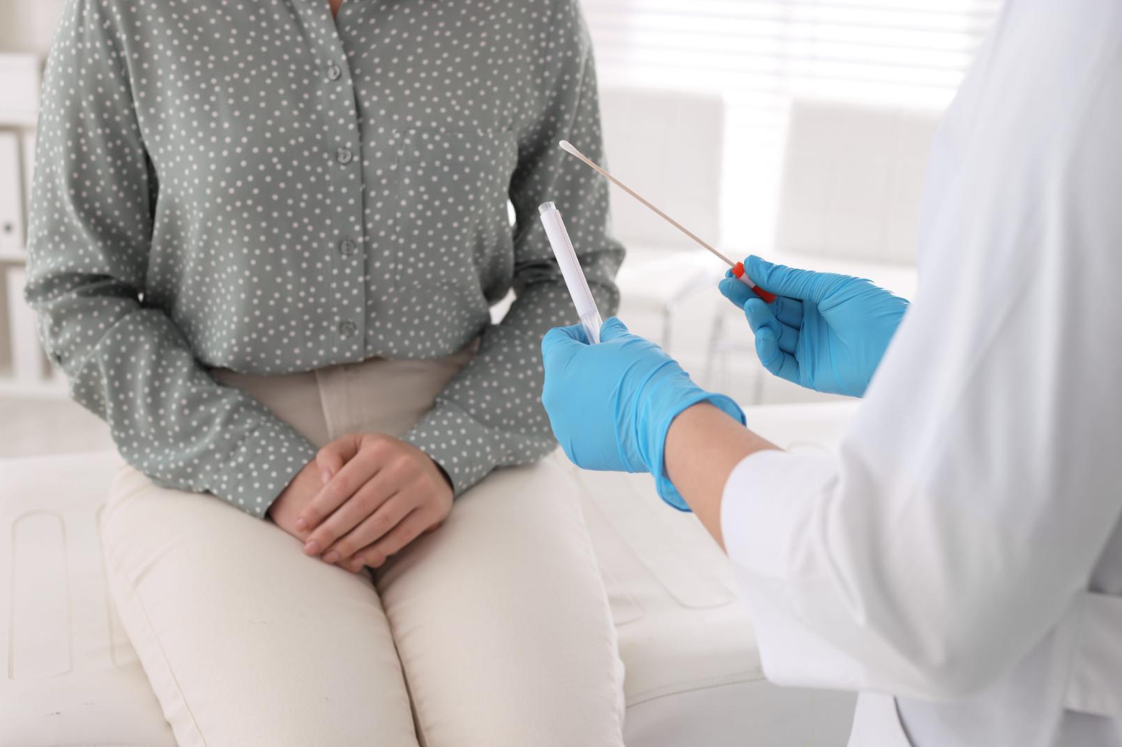 A doctor takes a sample from a woman for testing for signs of chlamydia.
