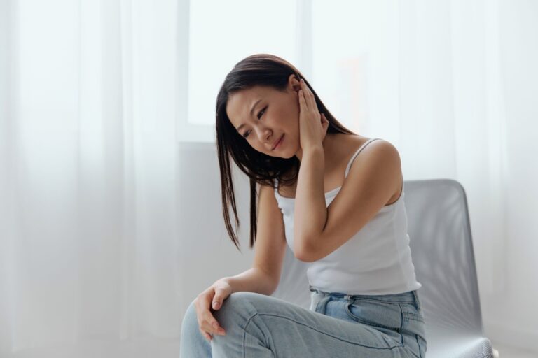 A woman suffering from a stiff neck, one of the symptoms of developing MenB.