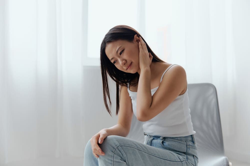 A woman suffering from a stiff neck, one of the symptoms of developing MenB.