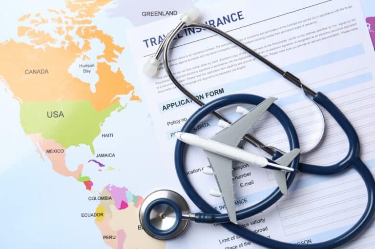 World map, stethoscope, and plane model beside a travel insurance form