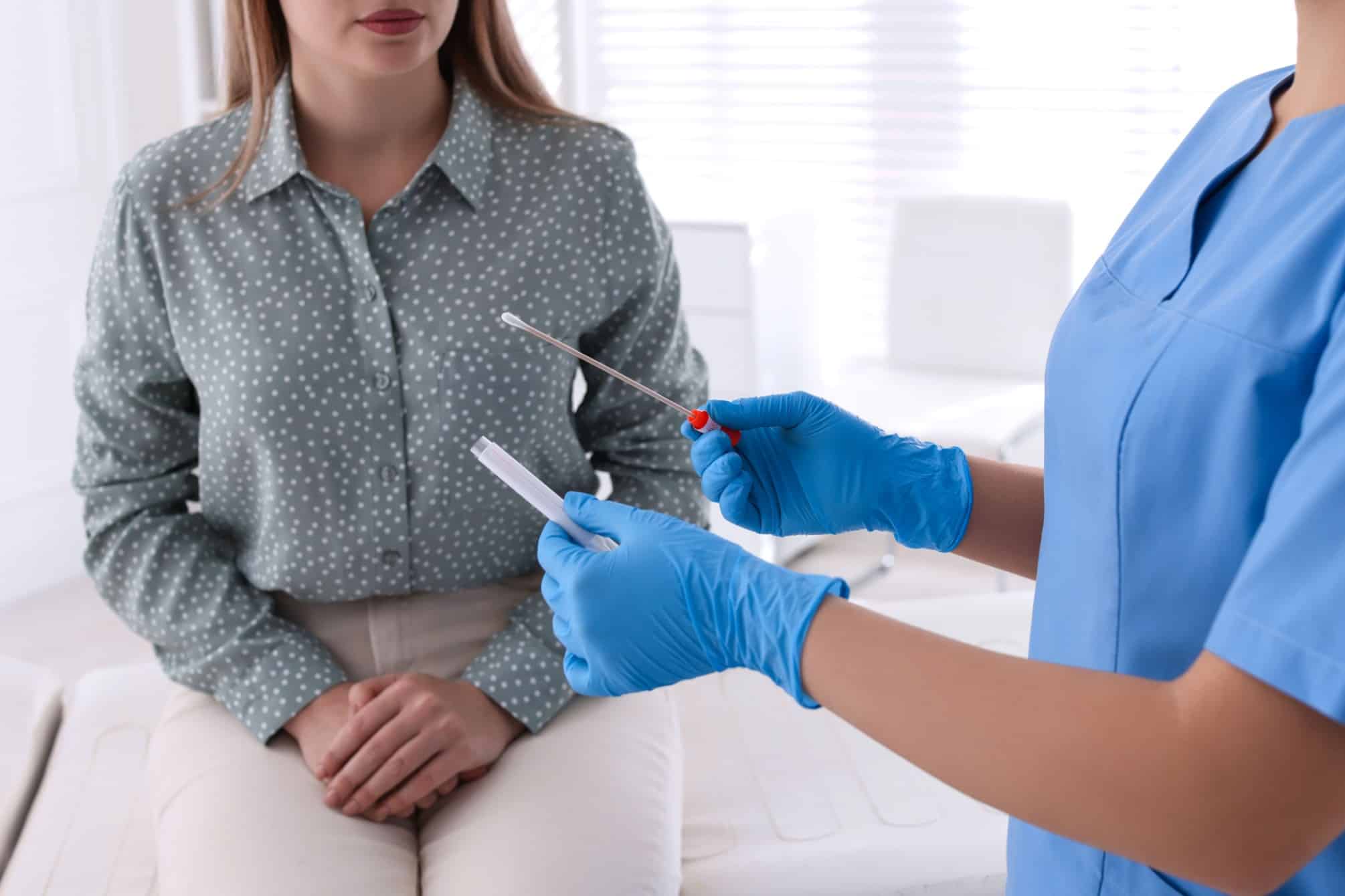 A doctor preparing to take a sample from a patient for STI testing