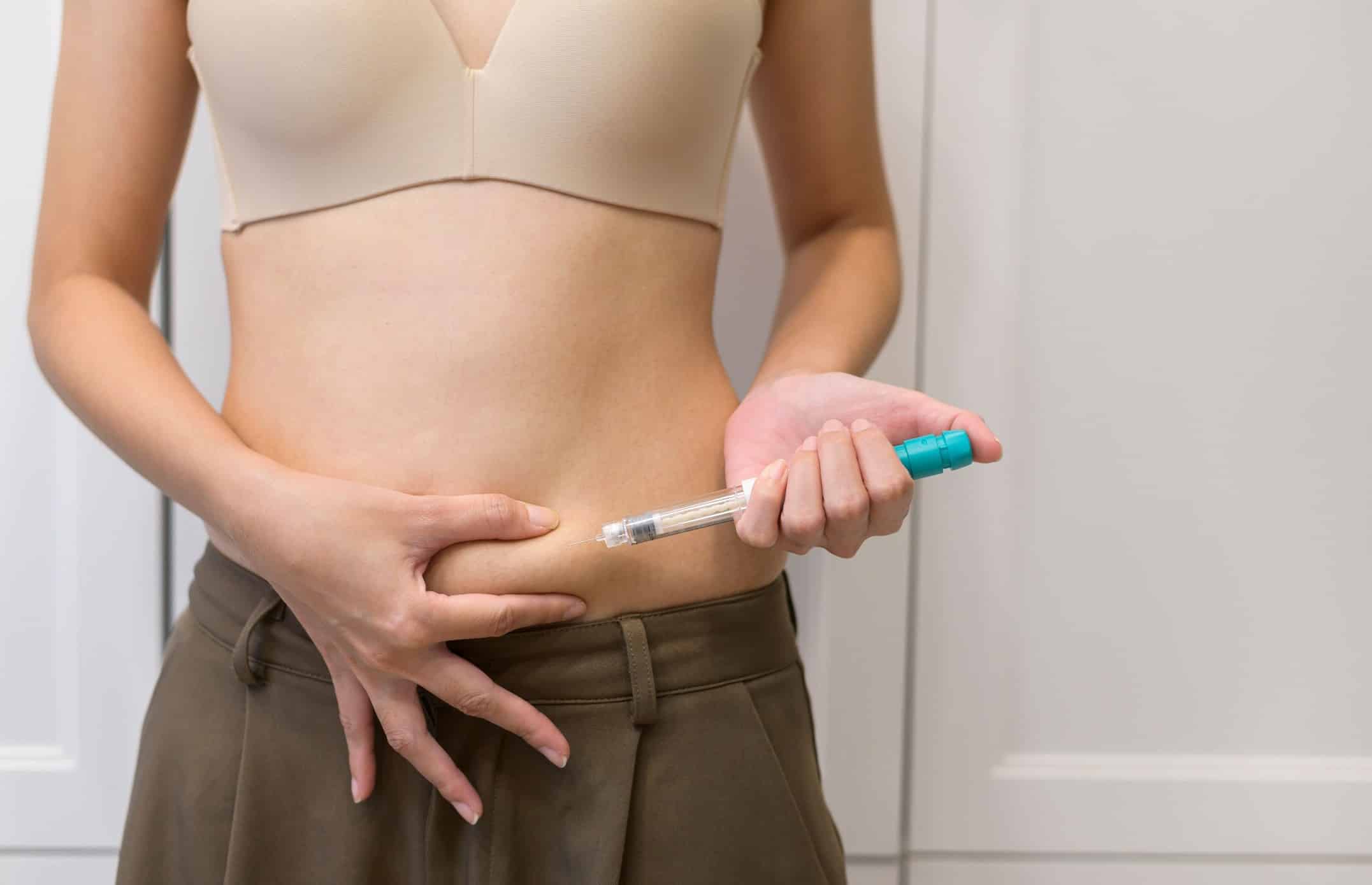 A woman administering a bremelanotide injection to her stomach area