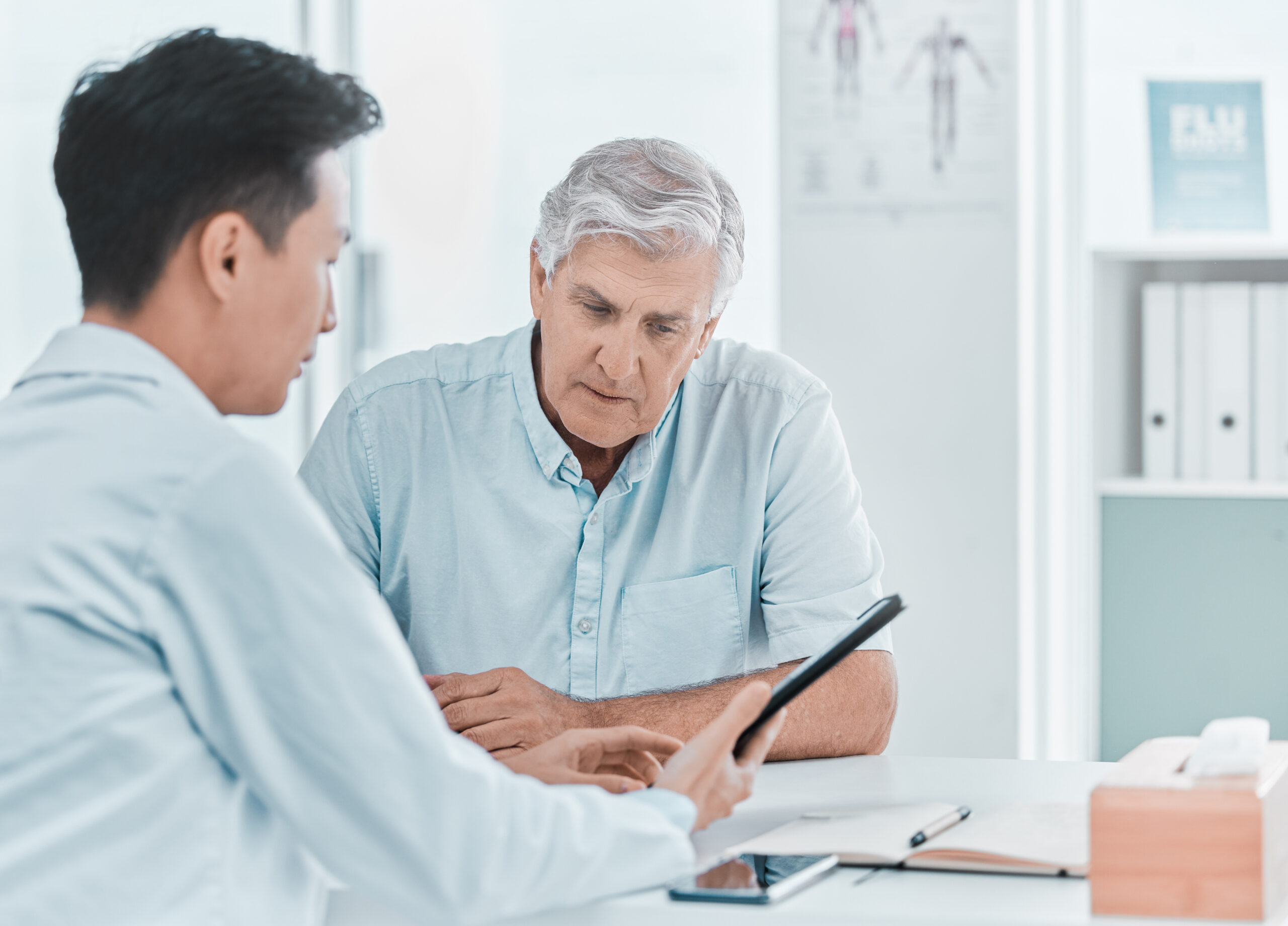 Doctor reviewing blood test results on a tablet with a male patient at a Bangkok men’s health clinic