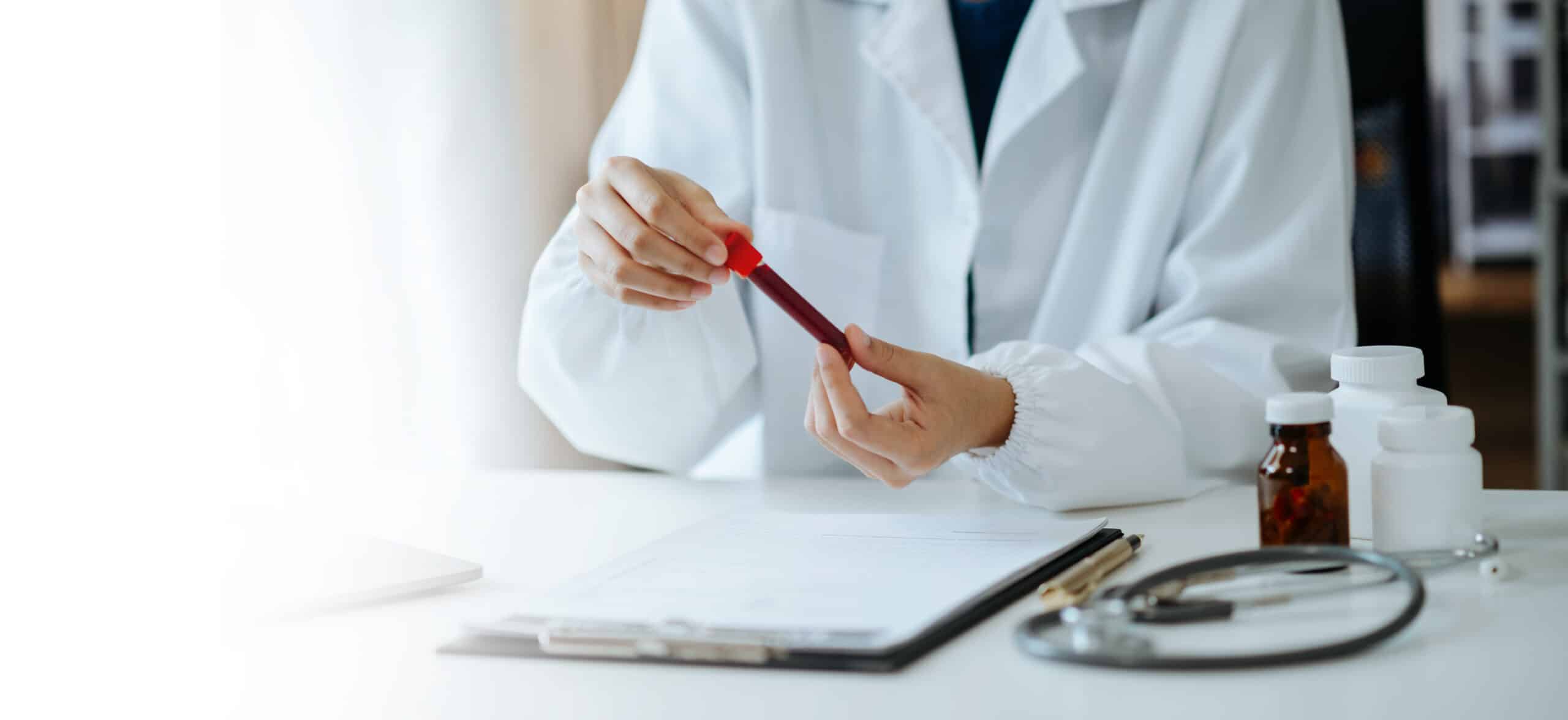 Medical professional reviewing a blood sample and clinical notes for ongoing TRT safety monitoring.