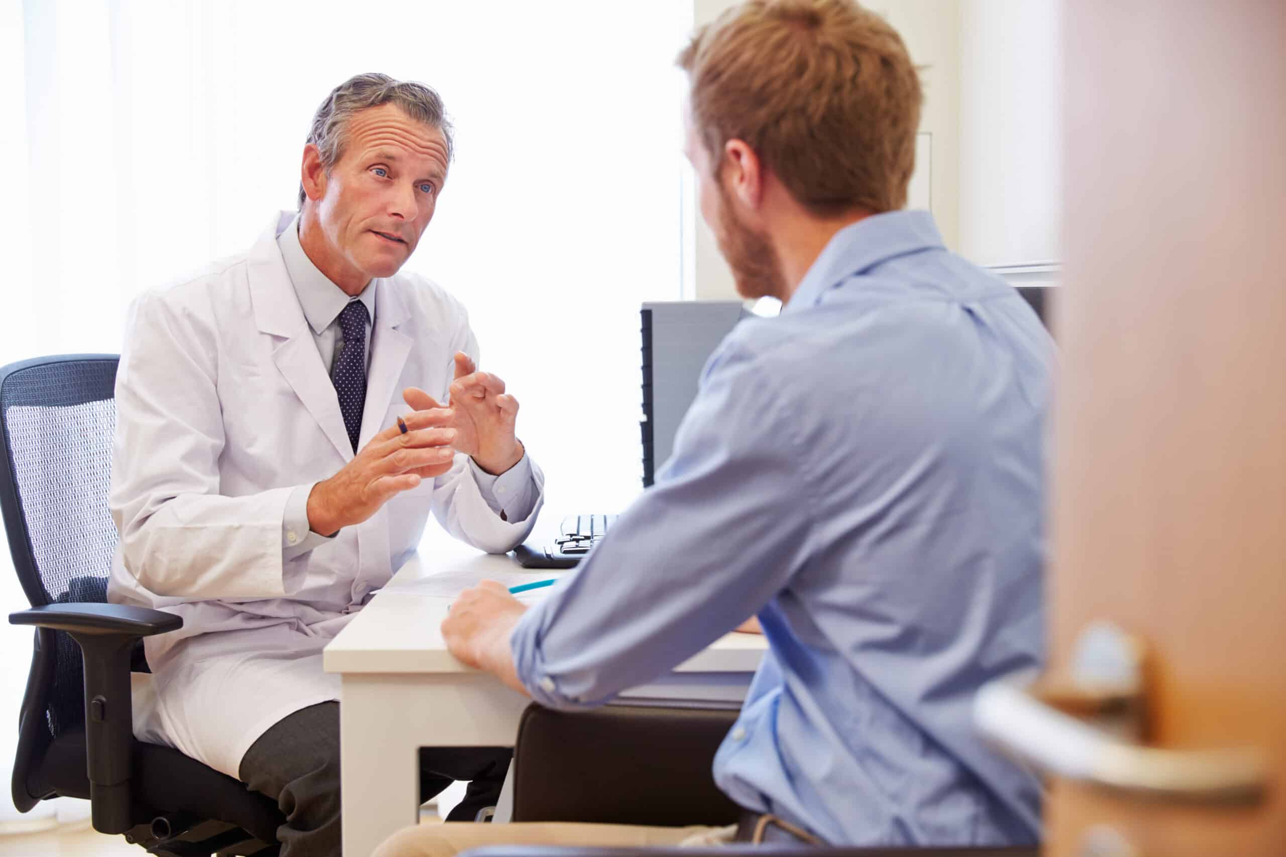 octor speaking with an adult male patient during a medical consultation.