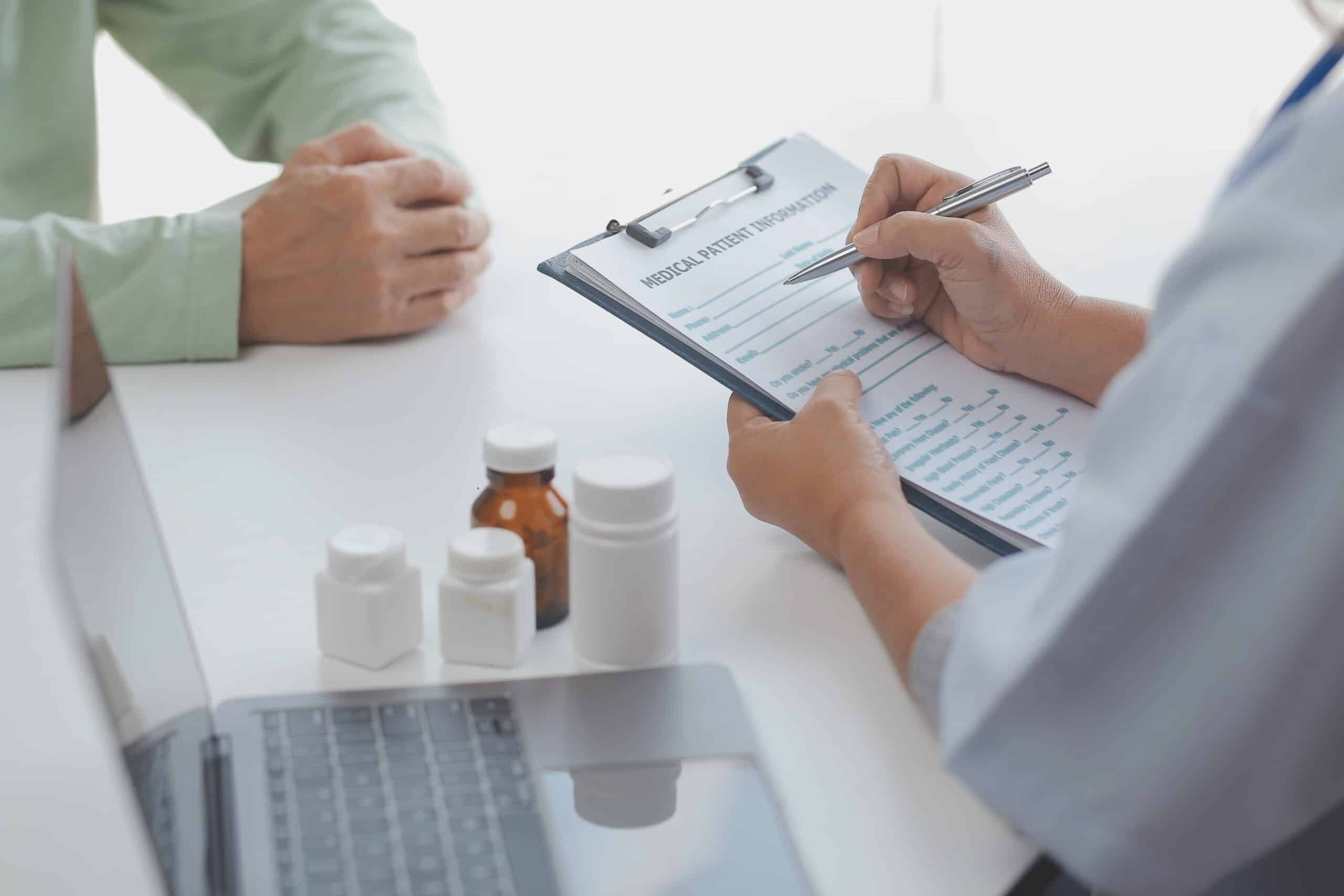 Clinician reviewing a patient information form with medicine bottles on the desk.